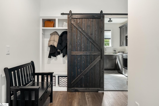 hallway with a barn door, wood finished floors, and a sink