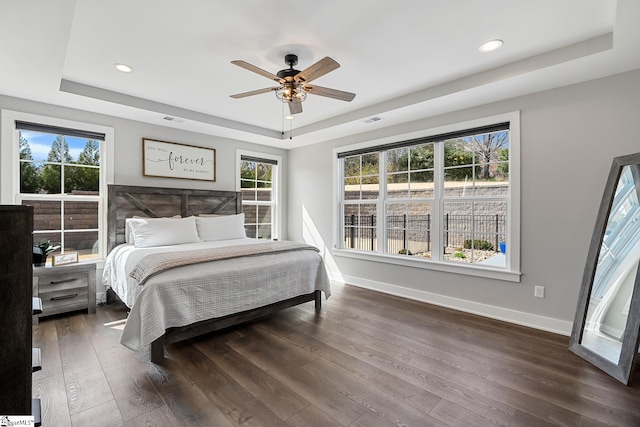 bedroom with baseboards, a tray ceiling, and hardwood / wood-style floors