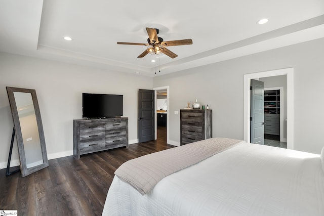 bedroom featuring recessed lighting, a tray ceiling, baseboards, and dark wood finished floors