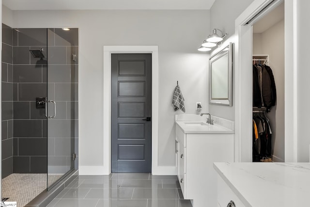 bathroom featuring a stall shower, vanity, a walk in closet, and baseboards