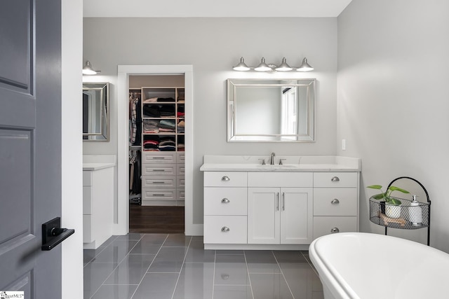 bathroom featuring tile patterned floors, vanity, a soaking tub, and a spacious closet