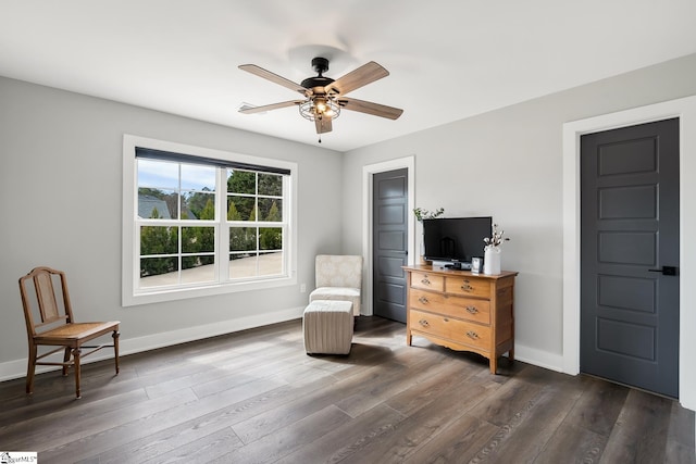 sitting room featuring ceiling fan, baseboards, and dark wood finished floors