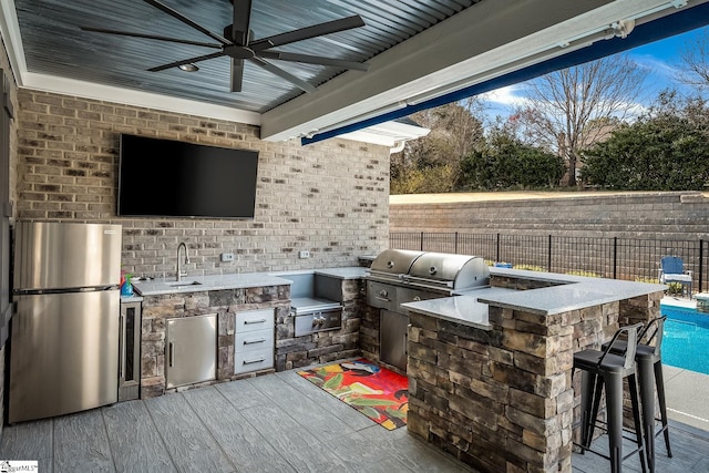 view of patio / terrace with outdoor wet bar, exterior kitchen, a ceiling fan, and fence