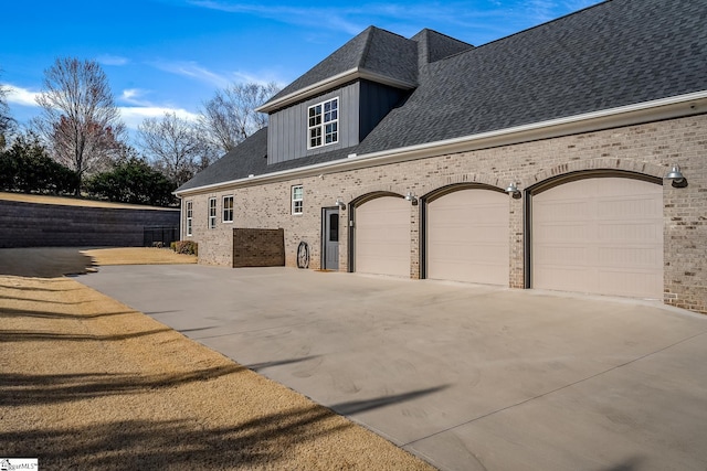 view of side of home featuring brick siding, driveway, an attached garage, and roof with shingles