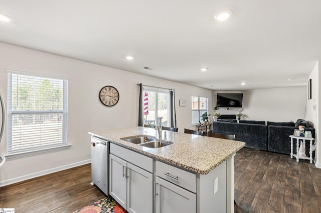 kitchen featuring visible vents, a kitchen island with sink, a sink, stainless steel dishwasher, and dark wood-style flooring