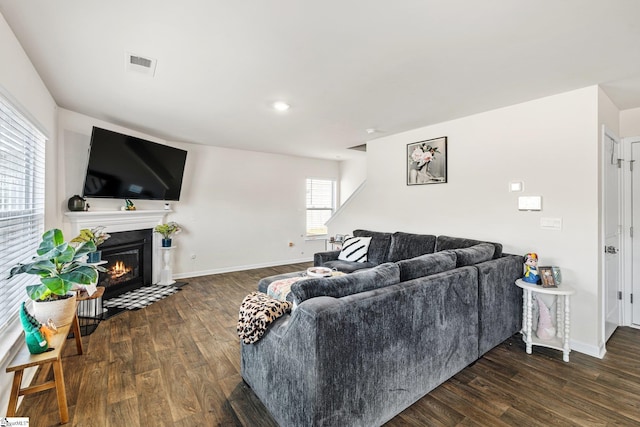 living room with visible vents, baseboards, a fireplace with flush hearth, and wood finished floors