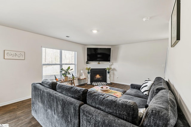 living area featuring dark wood finished floors, a fireplace with flush hearth, and baseboards