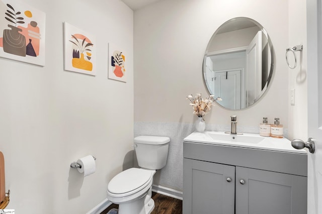 bathroom featuring toilet, vanity, baseboards, and wood finished floors