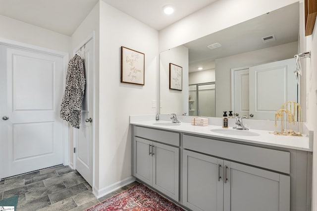 full bath featuring double vanity, visible vents, a stall shower, and a sink