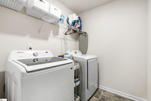 laundry area with laundry area, independent washer and dryer, stone finish flooring, and baseboards