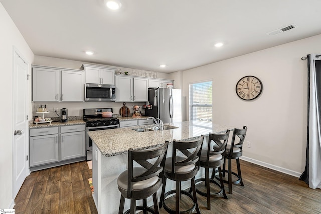 kitchen with visible vents, an island with sink, dark wood-style flooring, a sink, and appliances with stainless steel finishes