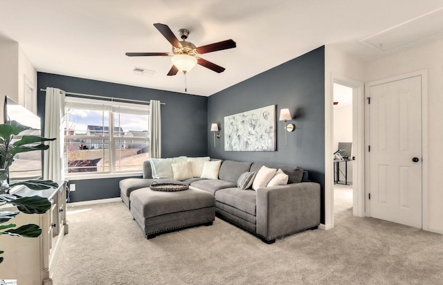 carpeted living area with visible vents, baseboards, attic access, and ceiling fan