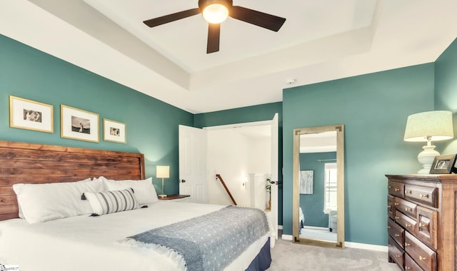 carpeted bedroom with baseboards, a raised ceiling, and ceiling fan