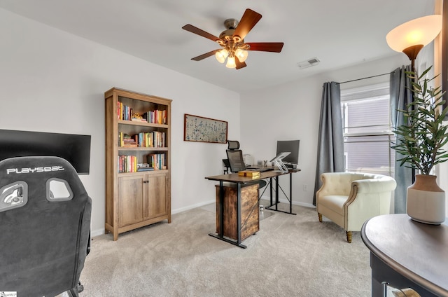 office space with light colored carpet, a ceiling fan, and baseboards