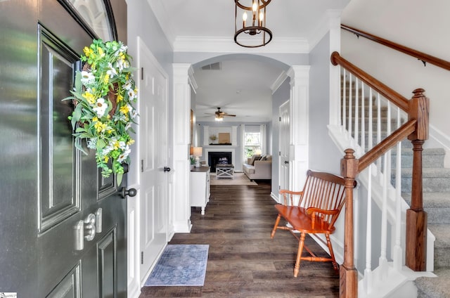 foyer entrance featuring a fireplace, visible vents, arched walkways, and ornamental molding