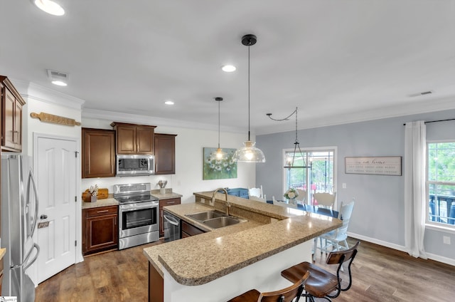 kitchen with visible vents, dark wood-type flooring, a sink, appliances with stainless steel finishes, and a breakfast bar area