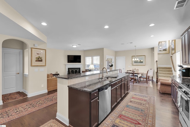 kitchen featuring visible vents, a sink, open floor plan, dark wood-style floors, and appliances with stainless steel finishes