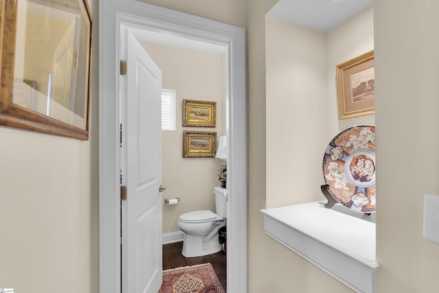 bathroom with toilet, baseboards, and wood finished floors