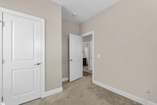 unfurnished bedroom featuring baseboards and light carpet