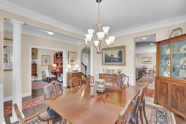 dining space featuring stairs, decorative columns, an inviting chandelier, wood finished floors, and arched walkways