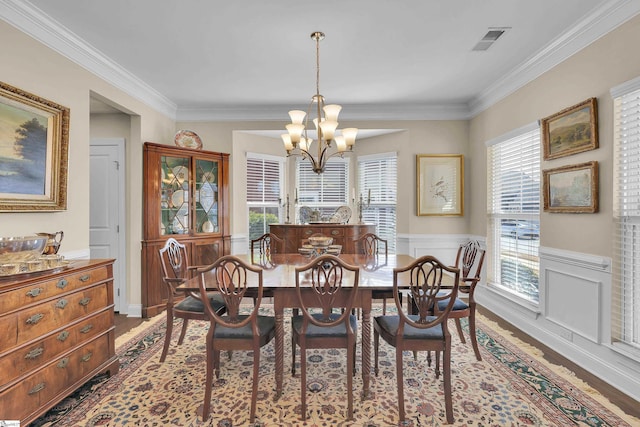 dining space with visible vents, dark wood finished floors, ornamental molding, wainscoting, and a notable chandelier