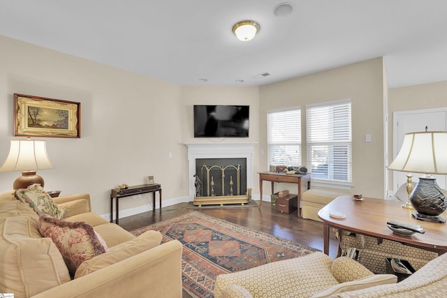 living area featuring wood finished floors, a fireplace, visible vents, and baseboards