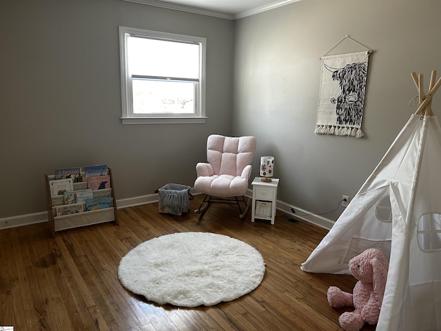 sitting room featuring baseboards, crown molding, and hardwood / wood-style flooring