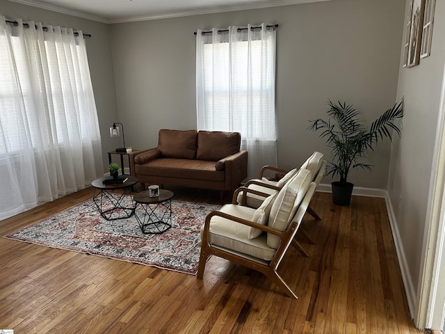 living room featuring a healthy amount of sunlight, crown molding, baseboards, and wood finished floors