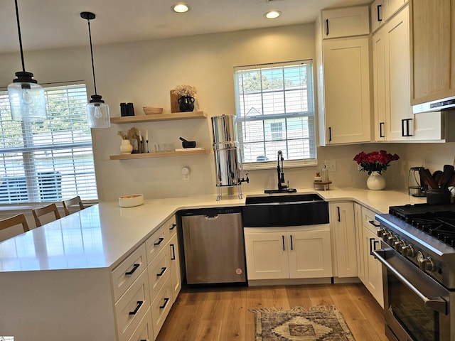 kitchen with light countertops, light wood-style floors, white cabinets, stainless steel appliances, and a sink