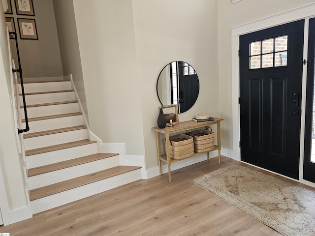 entrance foyer with stairway, baseboards, and wood finished floors