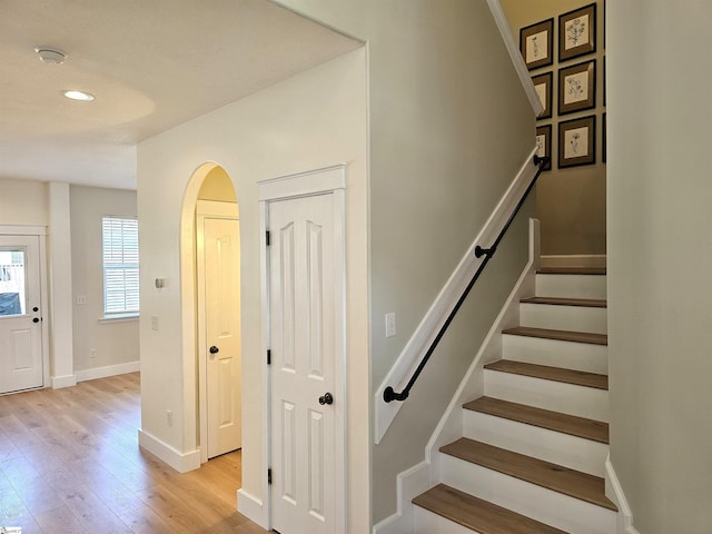 stairway featuring recessed lighting, wood finished floors, baseboards, and arched walkways