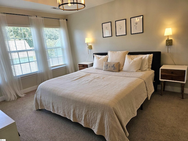 carpeted bedroom featuring a chandelier, visible vents, and baseboards