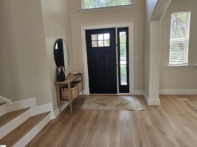 foyer featuring stairway, light wood-type flooring, and baseboards