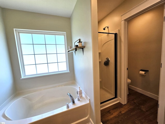 bathroom featuring a shower stall, baseboards, toilet, wood finished floors, and a bath