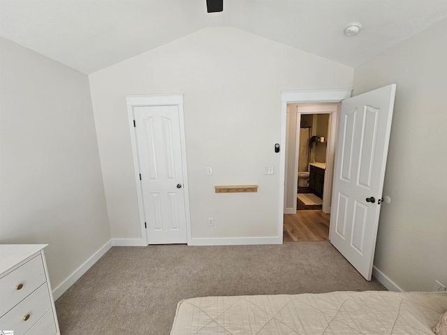 unfurnished bedroom featuring lofted ceiling, baseboards, and carpet floors