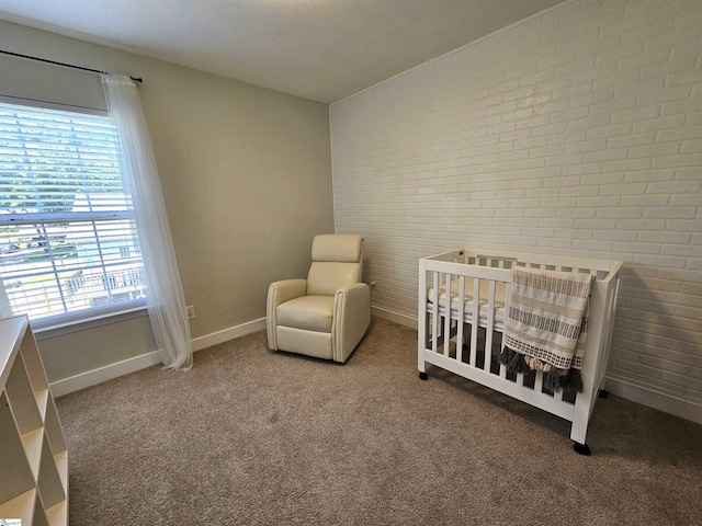 bedroom with a crib, carpet flooring, baseboards, and brick wall