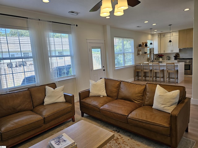 living area with light wood-type flooring, visible vents, a wealth of natural light, and recessed lighting