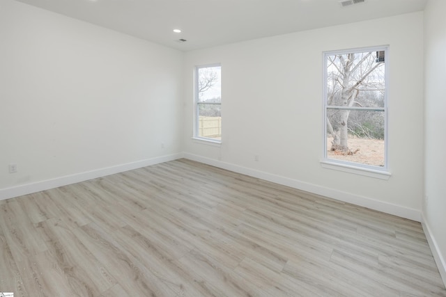 empty room featuring visible vents, wood finished floors, and baseboards