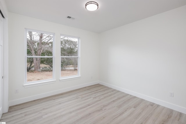 spare room featuring visible vents, light wood-type flooring, and baseboards