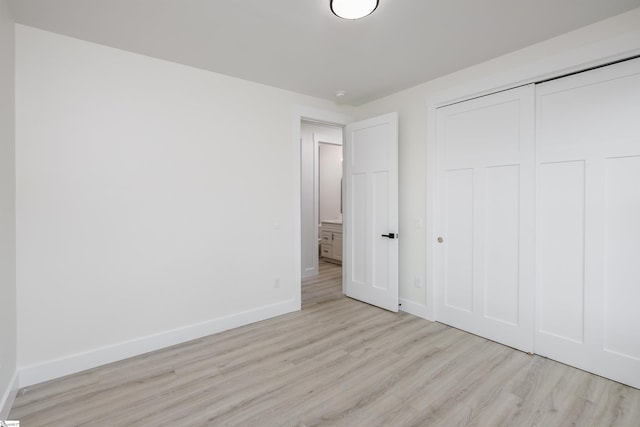 unfurnished bedroom with wood finished floors, baseboards, and a closet