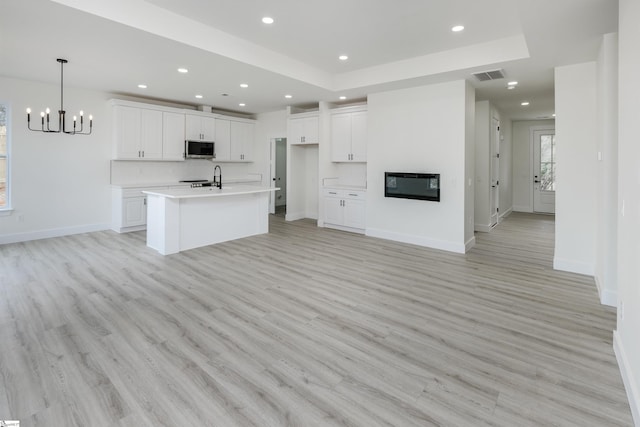 kitchen featuring recessed lighting, stainless steel microwave, a glass covered fireplace, and white cabinetry