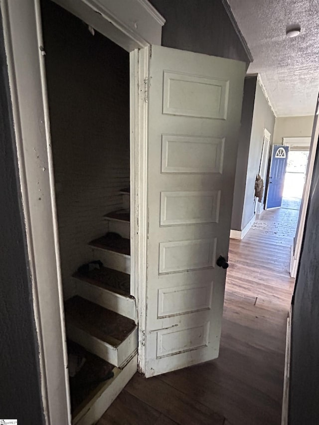 stairway featuring wood finished floors, baseboards, and a textured ceiling