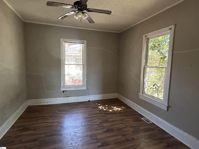 empty room with visible vents, dark wood-type flooring, baseboards, and ornamental molding