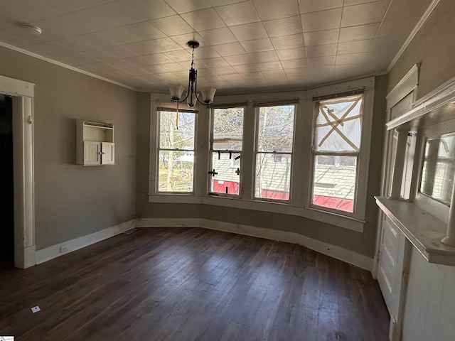 unfurnished dining area with an inviting chandelier, baseboards, crown molding, and dark wood-type flooring