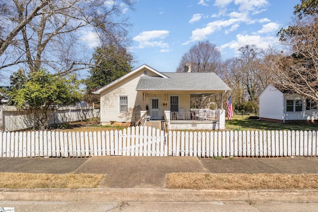 view of front of house featuring a fenced front yard, covered porch, and a shingled roof