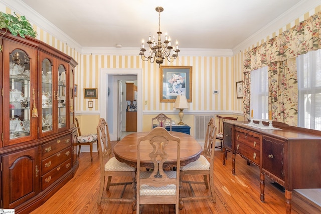 dining space with wallpapered walls, light wood-style floors, a wainscoted wall, and a chandelier