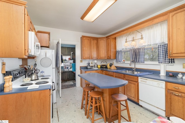 kitchen with light floors, white appliances, a breakfast bar area, and a sink