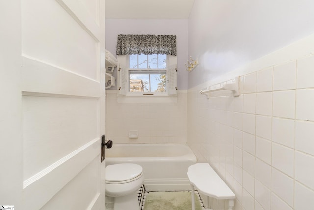 bathroom with a wainscoted wall, toilet, a tub, tile walls, and walk in shower