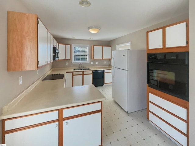 kitchen with light floors, light countertops, a peninsula, black appliances, and a sink