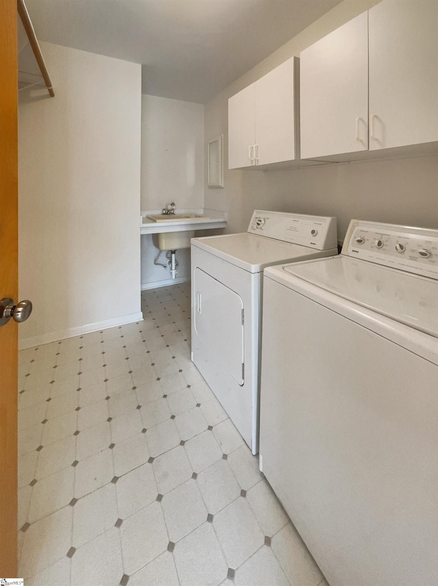 laundry area with baseboards, light floors, cabinet space, independent washer and dryer, and a sink